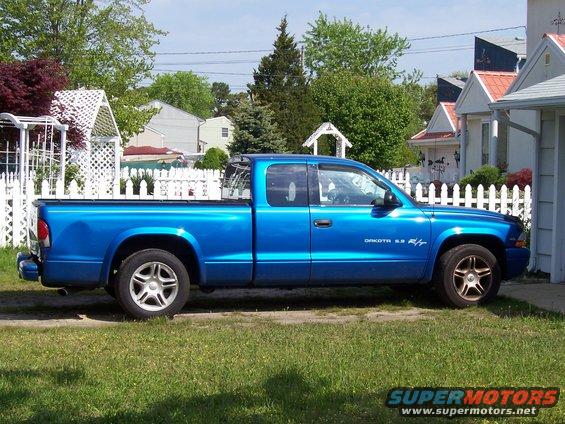 Blue pickup truck parked on grass, side view. Text on door reads 'DAKOTA 5.9 R/T'