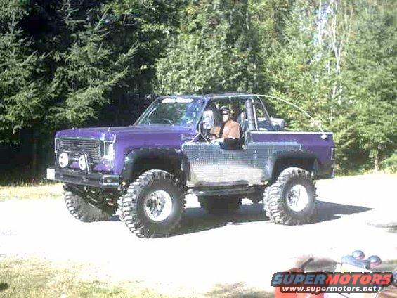 Purple off-road vehicle with chrome side panels and large tires, seen from a 3/4 front angle