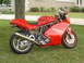 1985 Ford Bronco - A red Ducati Supersport 900 motorcycle is parked on a grassy lawn in front of a house.