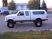 1992 Ford F-150 - Lifted 1992 Ford F-150 crew cab pickup truck with a camper shell is parked outside a house.