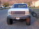 1992 Ford F-150 - This lifted 1992 Ford F-150 has a prominent chrome grille and is parked on a gravel surface.