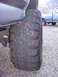 1992 Ford F-150 - A close-up view of the aggressive tread on a 1992 Ford F-150's off-road tire, with another truck visible in the background.