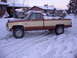 1992 Ford F-150 - A two-tone pickup truck sits in a snowy driveway, with a car parked behind it under a carport.