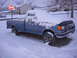 1992 Ford F-150 - A blue 1992 Ford F-150 pickup truck is parked on a snowy street, partially covered in snow.