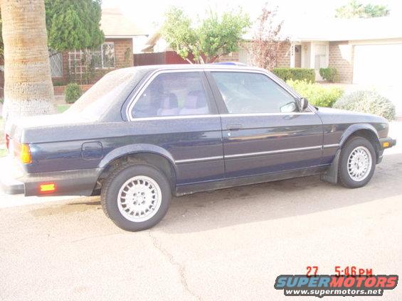Dark blue coupe with tinted windows and silver multi-spoke wheels parked on a paved surface