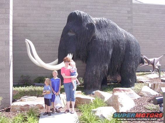 Mammoth statue with a family posing in front of a brick building