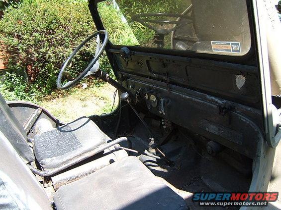 Jeep interior with black seats, steering wheel, and dashboard. A sticker is visible on the windshield