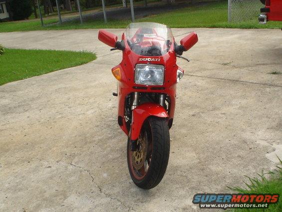 Red Ducati motorcycle front view, parked on concrete driveway