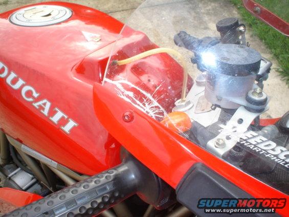 Red Ducati motorcycle fuel tank with white lettering and handlebars