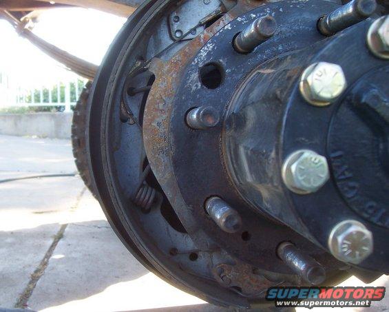 Close-up of a rear axle drum brake assembly with visible rust and leaf spring
