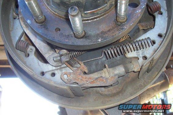 Rear drum brake assembly with rusty components and visible springs