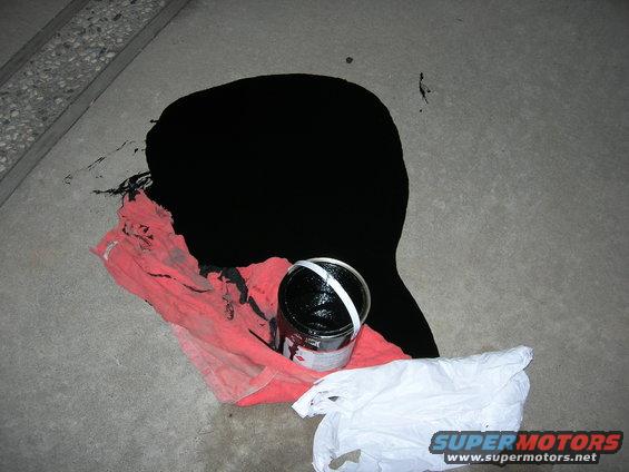 Spilled black paint on concrete with a can and rag