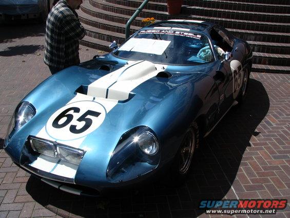 Blue race car with white stripes and number 65 on front