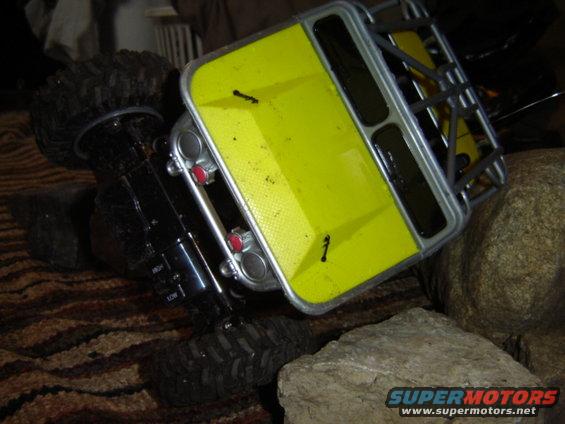 Yellow toy RC car body on its side, showing a silver roll cage and black interior with red lights