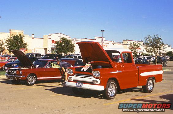 Red 1959 Chevrolet Apache pickup truck with hood open next to a red Ford Mustang with hood open