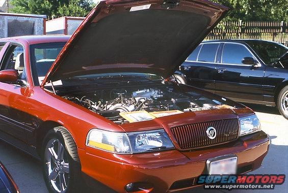 Red sedan's engine bay open, grille visible. Another black sedan behind