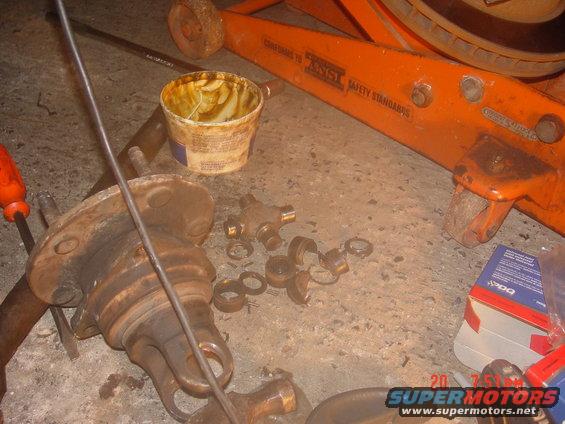 driveshaft U-joint, bearings, and grease tub on concrete floor next to orange jack