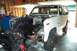 1985 Ford Bronco - 1985 Ford Bronco engine bay is open for repair work in a garage setting.