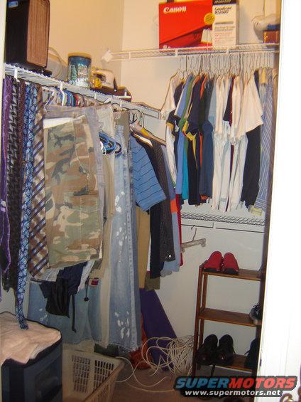 Closet interior with hanging clothes, ties, camouflage pants, and a Canon box