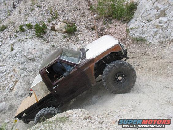 Brown and white off-road vehicle with large tires on a rocky incline