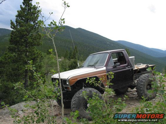 Modified pickup truck with large tires on a rocky mountain trail