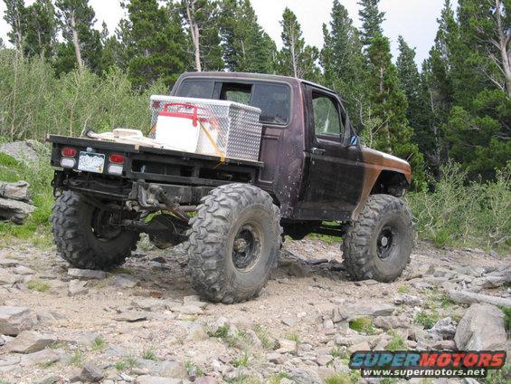 Modified pickup truck with flatbed and large tires on rocky terrain