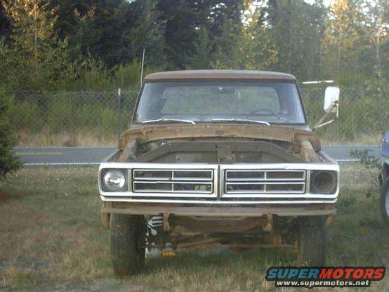Front view of a rusty 1973 Ford F-Series truck with its hood up. The grille is intact