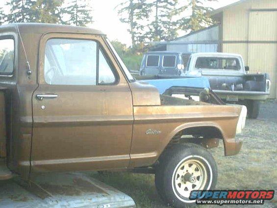 Side view of a brown 1972 Ford F-100 pickup truck with a blue tarp over the engine