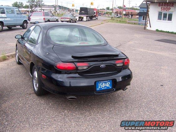 Rear view of a black 1996 Ford Taurus with a spoiler and Michigan plates
