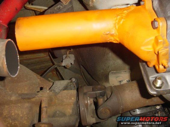 Close-up of a driveshaft connected to a differential, with an orange painted component above