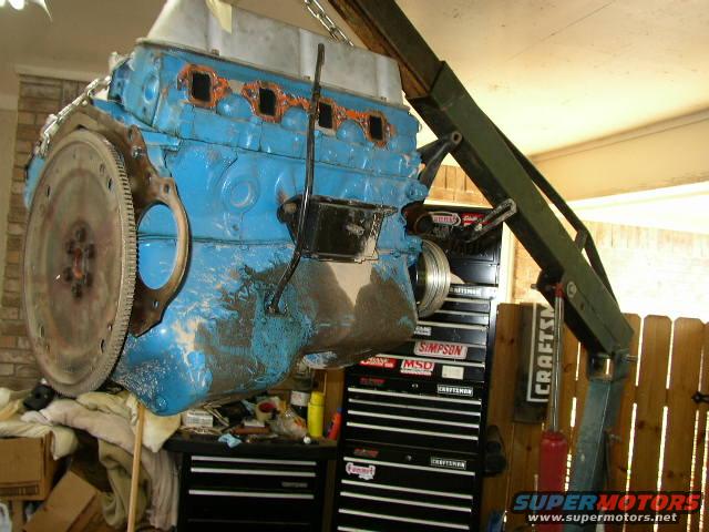 engine block being lifted by an engine hoist, with toolboxes in the background