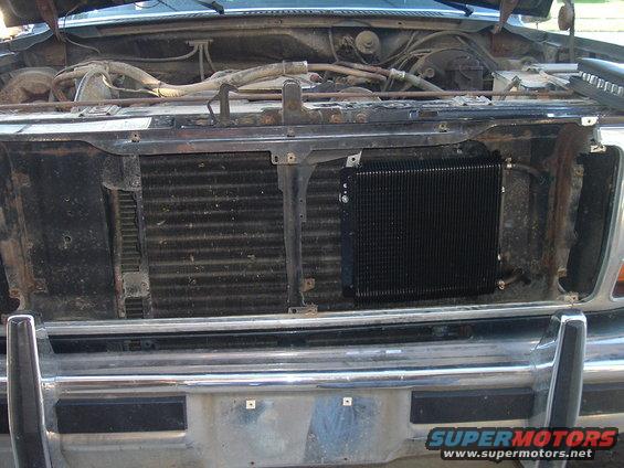Front of an older truck with hood open, showing radiator and an aftermarket transmission cooler. Chrome bumper visible