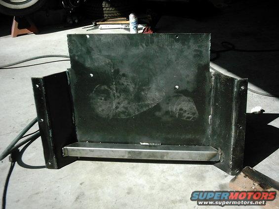 Black metal transfer skid plate with a silver metal bar across the bottom, showing some smudges and weld marks