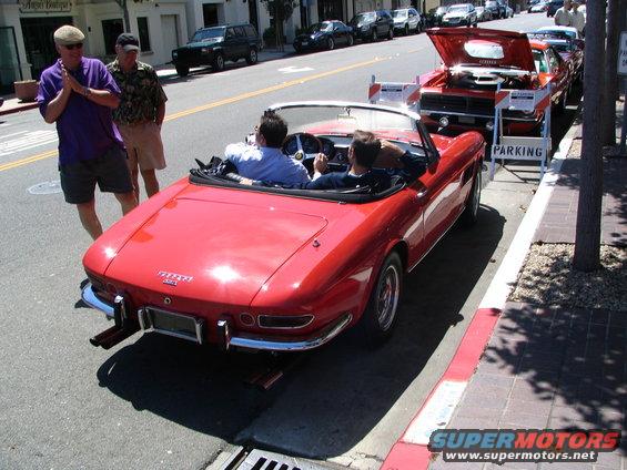 Red convertible with two people inside, parked on street