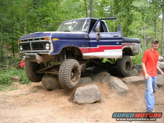 Blue and red 1977 Ford F-150 off-roading over rocks