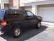 1996 Jeep Grand Cherokee - The side profile of a black Jeep Grand Cherokee shows its 4x4 badging and gold-colored wheels.