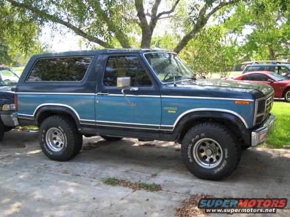 1982 Ford Bronco parked on concrete, blue and black two-tone paint, chrome trim