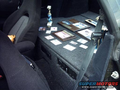 Car interior with seats, custom carpeted storage, and several awards and cards laid out