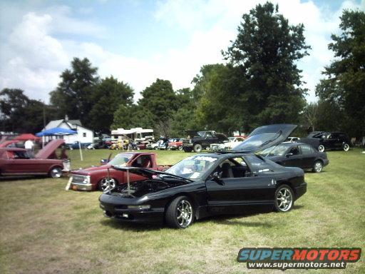 Black 1995 Ford Probe with hood open parked on grass at a car show