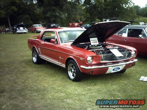 Red 1965 Ford Mustang coupe, hood open, showing engine and Ford badge