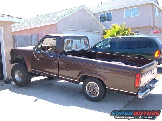 Brown pickup truck, lifted, with chrome trim and aftermarket wheels, parked in a driveway