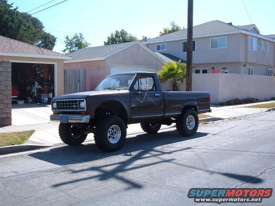 Lifted 1985 Ford Ranger pickup truck parked on street, front 3/4 view