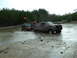 1995 Ford Bronco - A 1995 Ford Bronco and a Jeep are stuck in a muddy off-road area, with the Bronco partially submerged.