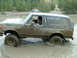 1995 Ford Bronco - Muddy 1995 Ford Bronco navigating through a water obstacle with another vehicle visible in the distance.
