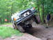 1979 Ford Bronco - This black SUV is tilted precariously on a dirt trail, with its front grille and off-road tires clearly visible.