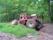 1979 Ford Bronco - A custom-built off-road buggy with a roll cage is shown traversing a challenging dirt path in a wooded area.
