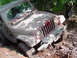 1979 Ford Bronco - A Jeep Wrangler is stuck in the mud, with two people standing in the background.