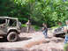 1979 Ford Bronco - Two off-road vehicles are stuck in the mud on a wooded trail, with people attempting to free them.