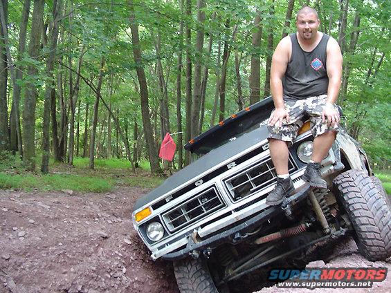 Gray 1979 Ford Bronco front grille with a man sitting on the hood