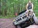 1979 Ford Bronco - A man sits atop the grille of a gray 1979 Ford Bronco as it navigates an off-road trail.